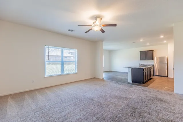 a view of an empty room with a window and a kitchen