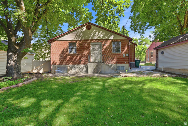 270 East 700 North Logan, UT 84321 - Photo 33 of 42 Spacious backyard featuring a lush lawn, mature shade trees, a brick exterior, a concrete patio, and a separate garage structure