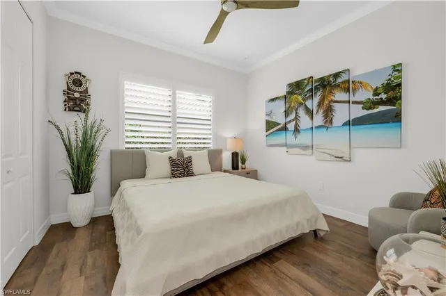 a bedroom with a large bed a potted plant and a window
