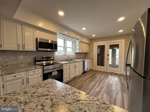 an empty room with wooden floor chandelier fan and windows