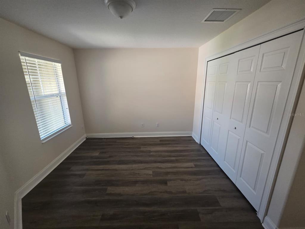 6930 Piazza Street Orlando, FL 32819 - Photo 19 of 25 a view of an empty room with wooden floor and a window