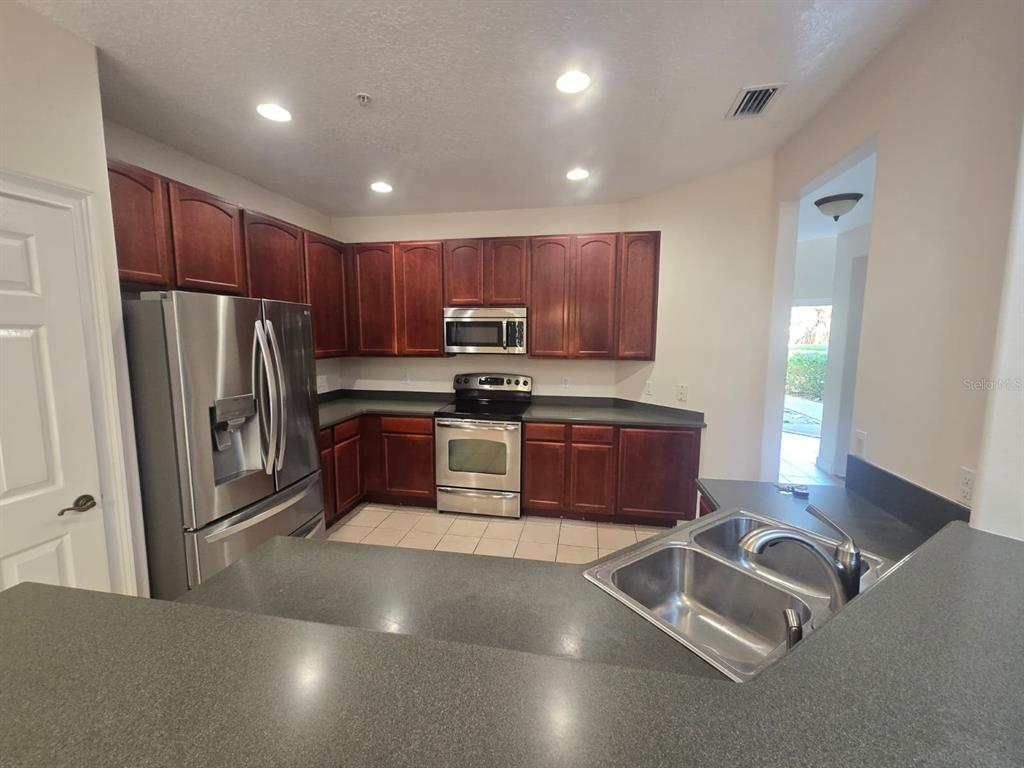 6930 Piazza Street Orlando, FL 32819 - Photo 8 of 25 a kitchen with granite countertop a refrigerator and a sink