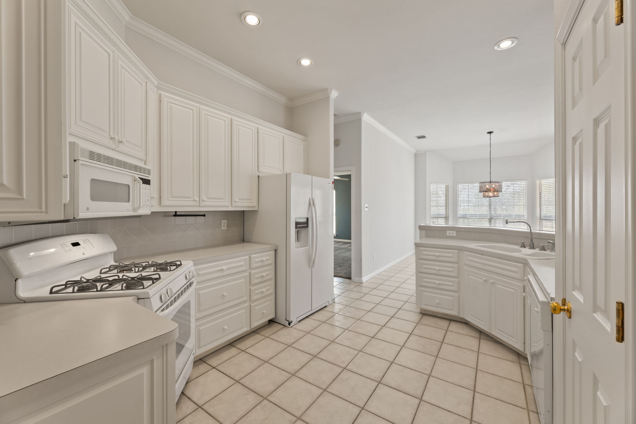 109 Riverview Drive Georgetown, TX 78628 - Photo 16 of 35 Kitchen with white appliances, white cabinetry, light countertops, ornamental molding, and backsplash