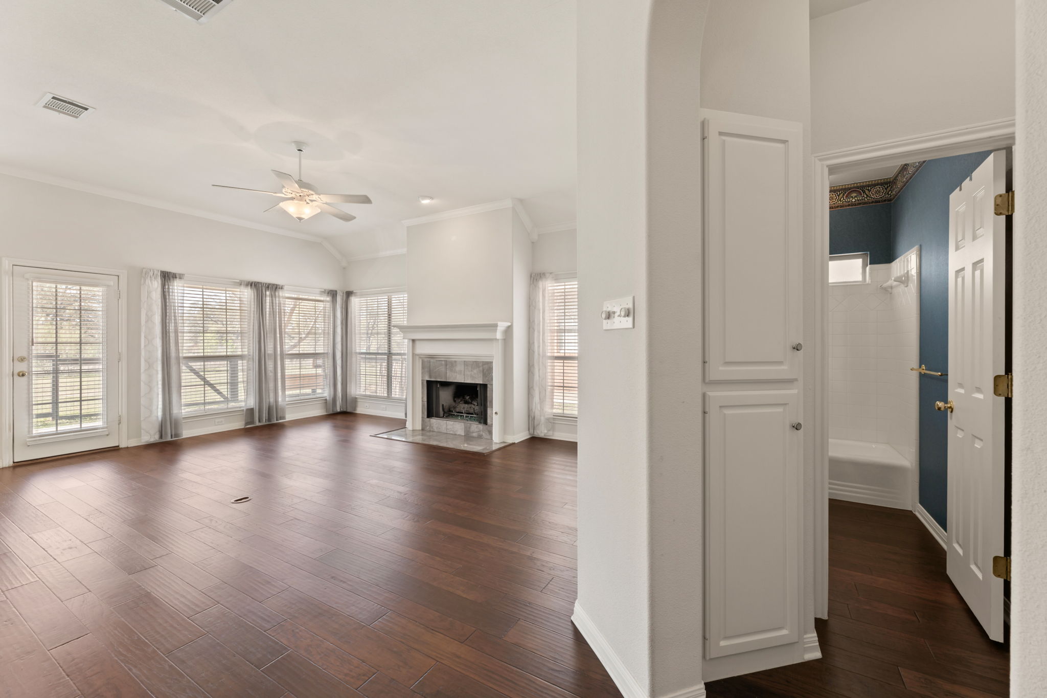 109 Riverview Drive Georgetown, TX 78628 - Photo 8 of 35 Unfurnished living room featuring a ceiling fan, dark wood-style floors, crown molding, lofted ceiling, and a fireplace