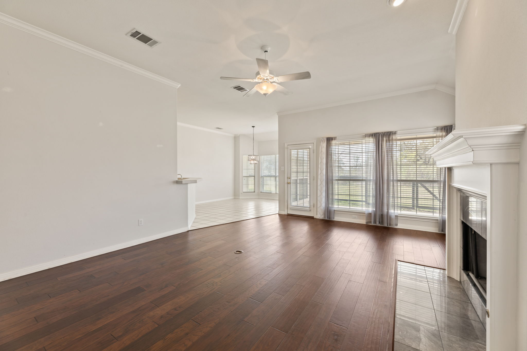 109 Riverview Drive Georgetown, TX 78628 - Photo 10 of 35 Unfurnished living room with ceiling fan, crown molding, a fireplace, and dark wood-type flooring