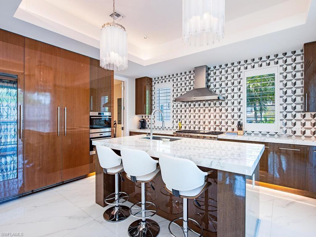 490 5th Street South, Unit 101 Naples, FL 34102 - Photo 5 of 34 a kitchen with a dining table chairs cabinets and stainless steel appliances