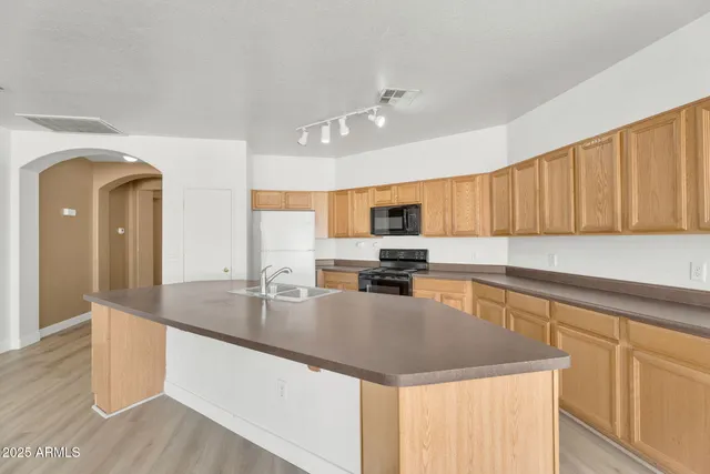 an empty room with wooden floor hallway and a chandelier fan