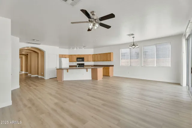 an empty room with wooden floor and a ceiling fan