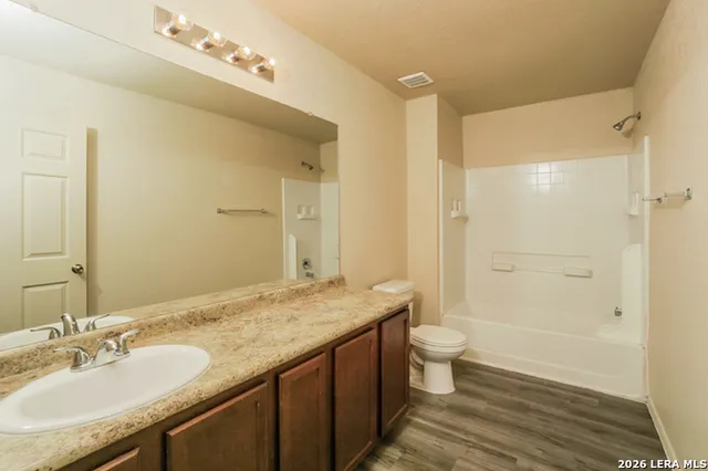 a bathroom with a granite countertop sink a toilet a mirror and shower