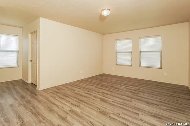 an empty room with wooden floor and windows