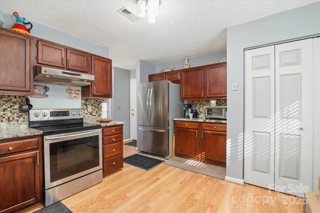 a kitchen with stainless steel appliances granite countertop a refrigerator stove and sink