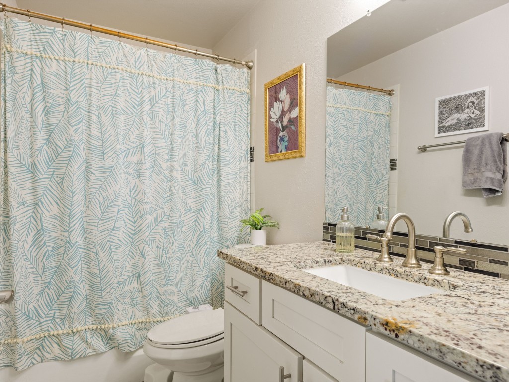 1307 East St Johns Avenue, Unit B Austin, TX 78752 - Photo 16 of 27 a bathroom with a granite countertop sink a toilet and a mirror