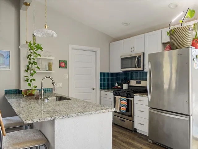 a kitchen with kitchen island granite countertop a refrigerator a stove and a sink