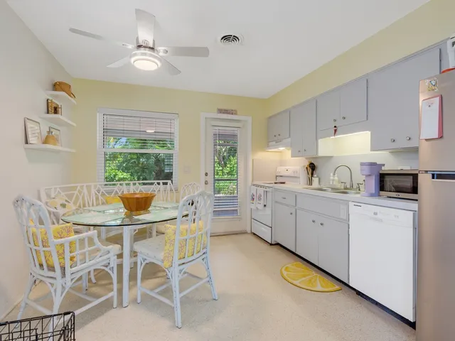 a kitchen with stainless steel appliances granite countertop a dining table chairs refrigerator and cabinets
