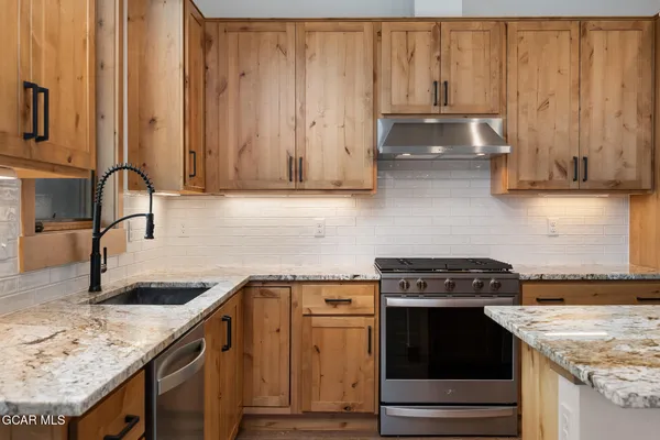 a kitchen with granite countertop a sink stove and cabinets
