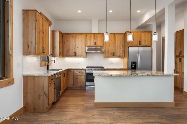 a kitchen with stainless steel appliances granite countertop a sink a stove and a refrigerator