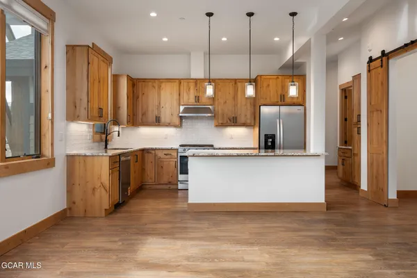 a large kitchen with stainless steel appliances a large counter top a stove a sink and a refrigerator