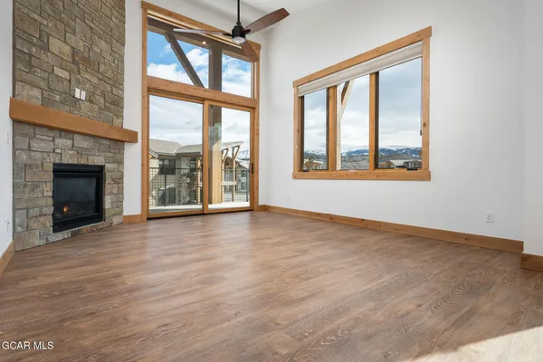 an empty room with wooden floor fireplace and windows