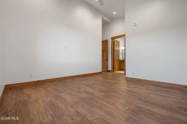 a view of an empty room with wooden floor and closet