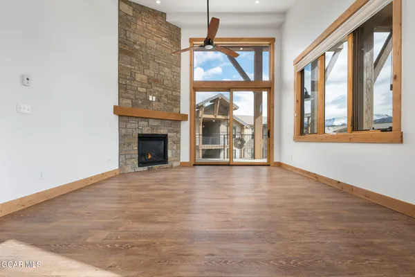 an empty room with wooden floor fireplace and windows