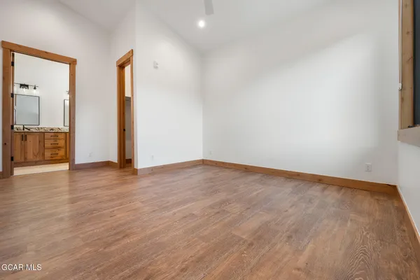 a view of an empty room with wooden floor and closet