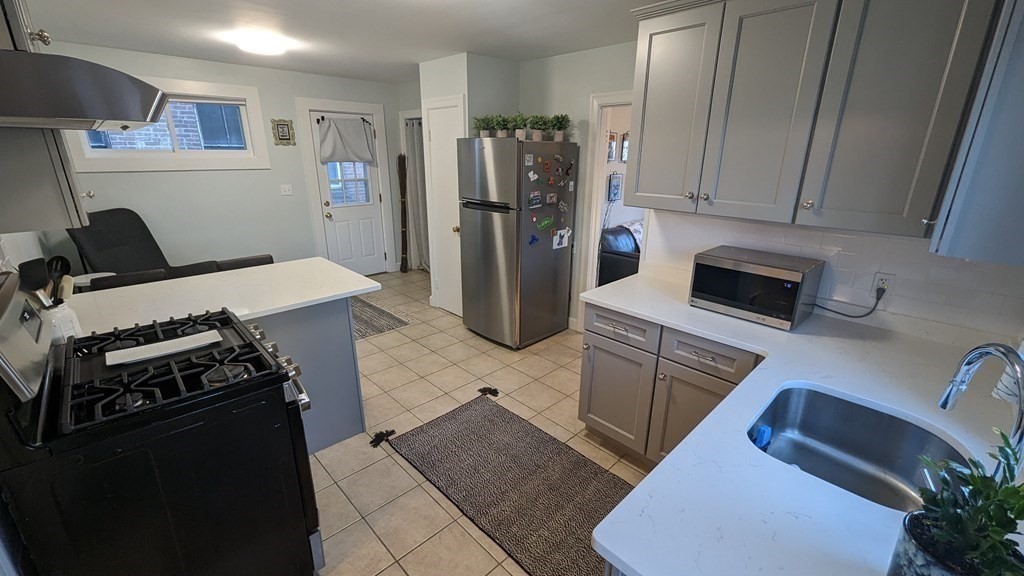975 Chestnut Street, Unit R Newton, MA 02464 - Photo 3 of 8 a kitchen with stainless steel appliances kitchen island granite countertop a refrigerator stove and sink