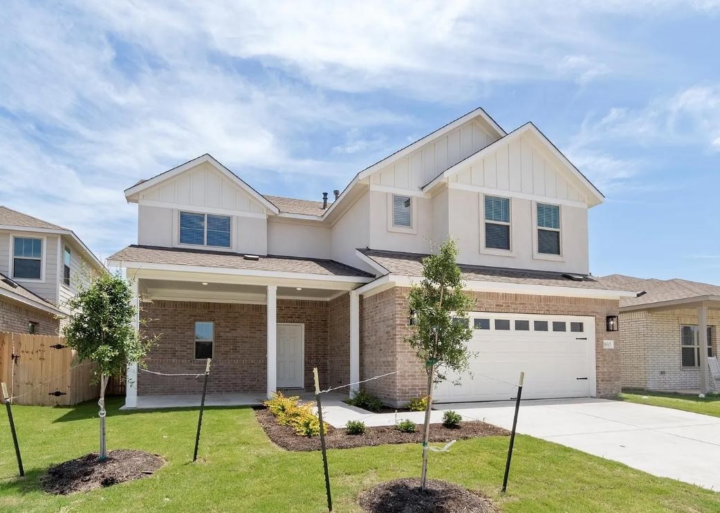 View of front of home featuring board and batten siding, brick siding, concrete driveway, a garage, and a patio area