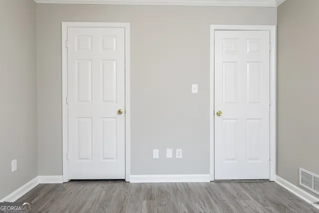 an empty room with wooden floor and closet area