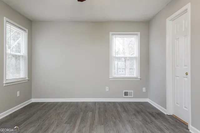 an empty room with wooden floor and windows