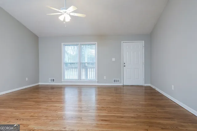 a view of an empty room with wooden floor and a window