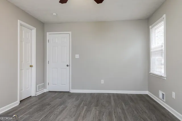 an empty room with wooden floor and windows