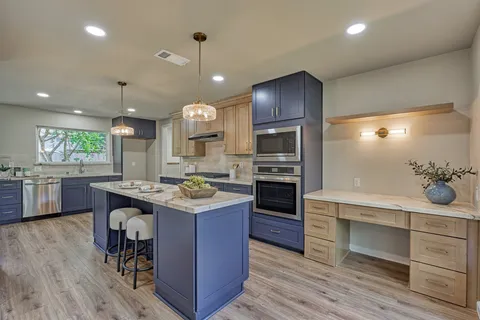 a kitchen with kitchen island granite countertop a sink counter and chairs