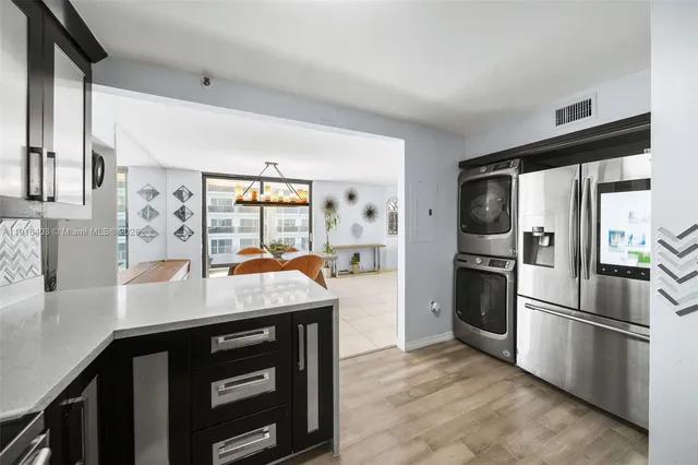 a kitchen with stainless steel appliances kitchen island granite countertop a refrigerator a stove and a sink with wooden floor