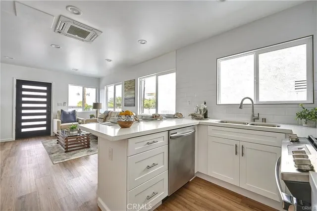 a kitchen with a stove a sink and white cabinets with wooden floor