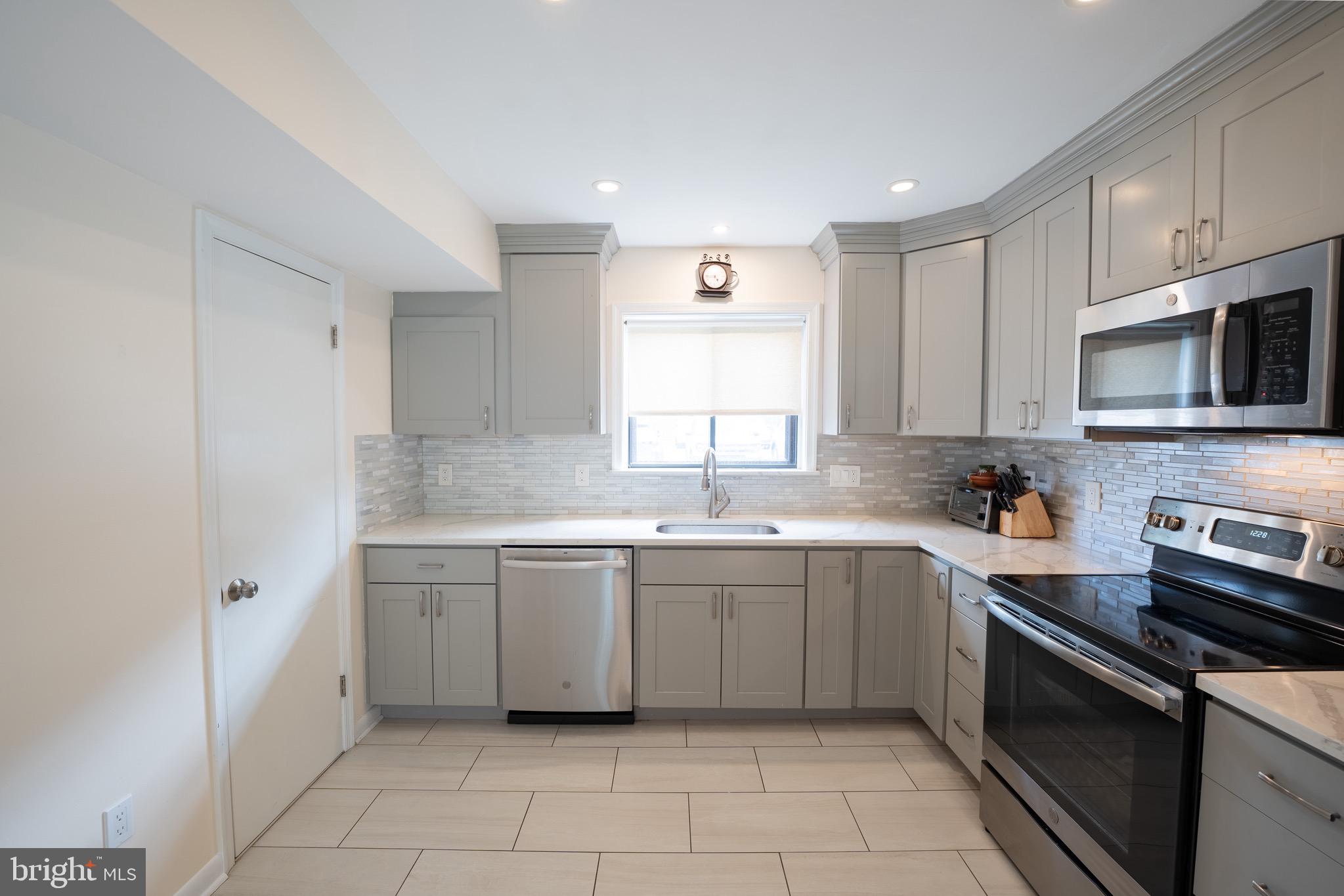10 Brian Court, Unit 242 Gaithersburg, MD 20877 - Photo 11 of 28 a large white kitchen with a sink and dishwasher a stove top oven with wooden floor