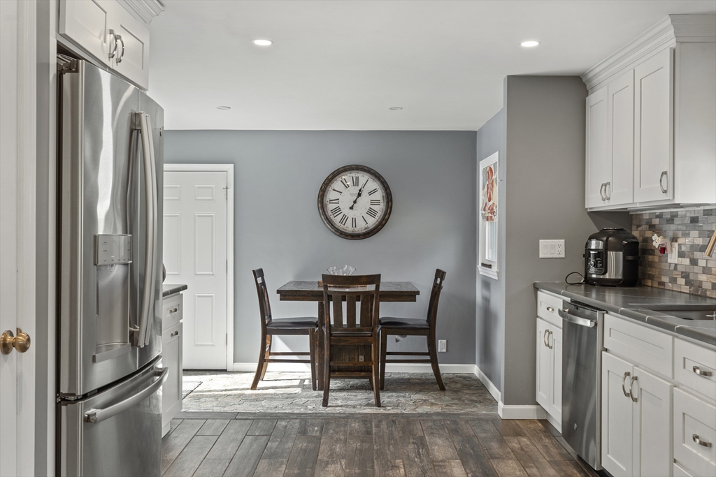 27 Leo's Lane Avon, MA 02322 - Photo 5 of 30 a kitchen with stainless steel appliances granite countertop a refrigerator a stove a dining table and chairs with wooden floor