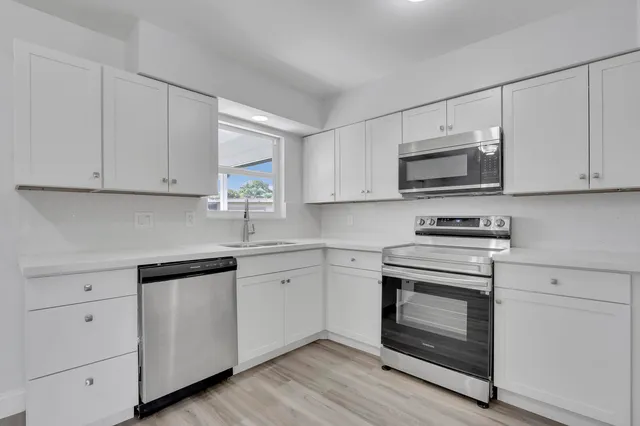 a kitchen with cabinets appliances a sink and a window
