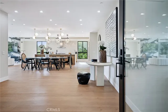 a dining hall view with a large dining table and a large window with stainless steel appliances