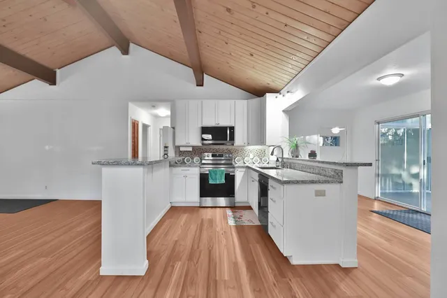 a kitchen with stainless steel appliances granite countertop wooden floors a stove and white cabinets