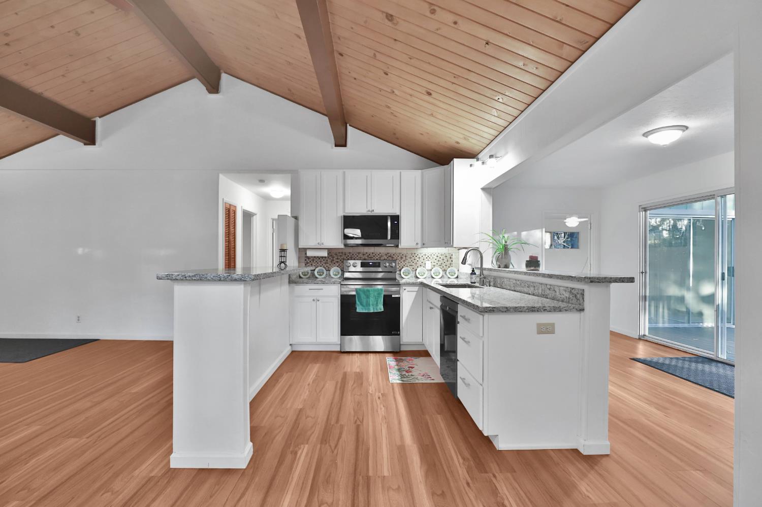 3060 Leaf Circle Pollock Pines, CA 95726 - Photo 8 of 38 a kitchen with stainless steel appliances granite countertop wooden floors a stove and white cabinets