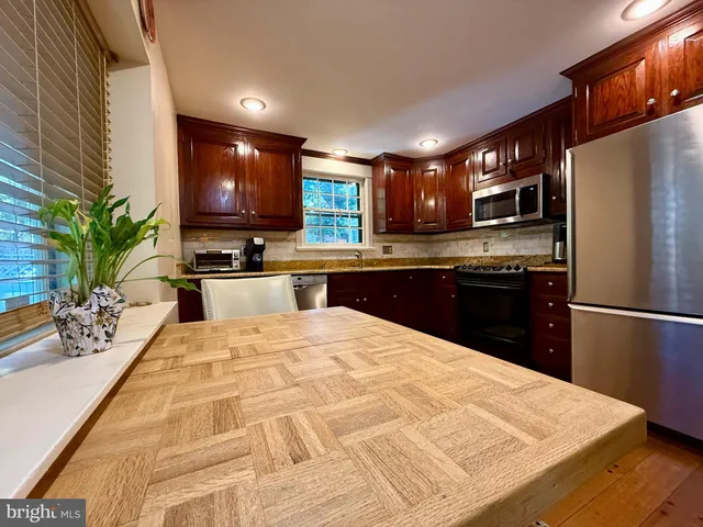 a kitchen with stainless steel appliances granite countertop a refrigerator a sink a stove a microwave a dining table and chairs