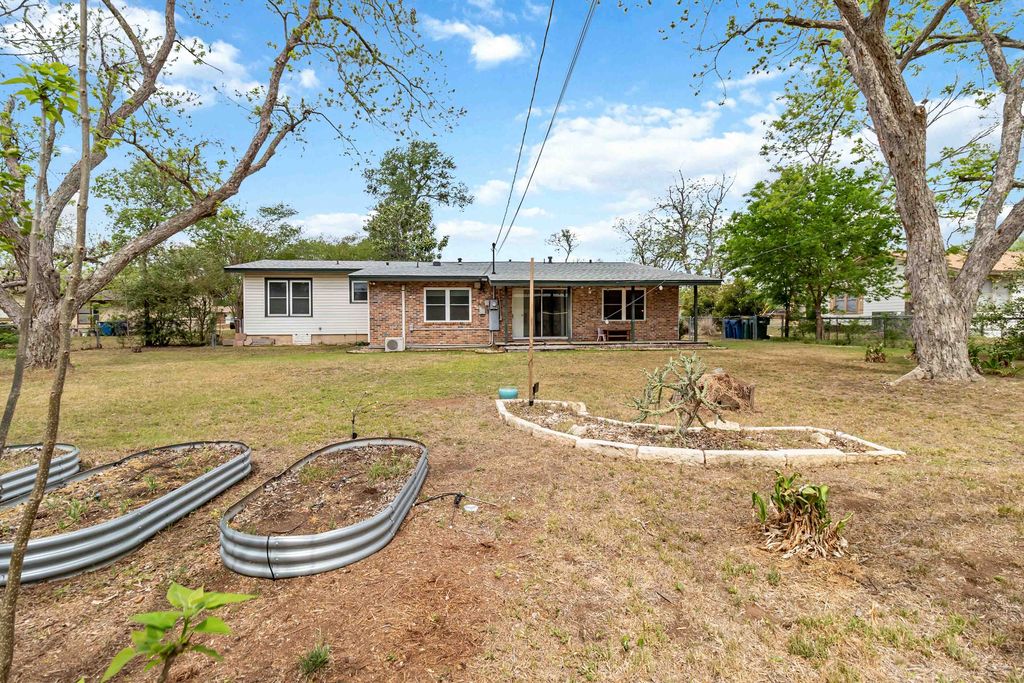 605 West 11th Street Elgin, TX 78621 - Photo 29 of 31 Back of house with a lawn, a vegetable garden, brick siding, and a patio