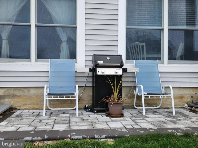 a view of a white house with large windows and a table and chairs under an umbrella