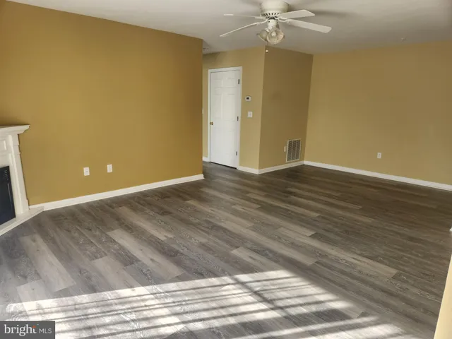 a view of a room with wooden floor and a ceiling fan