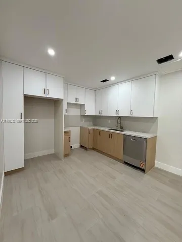 a large kitchen with a large counter top a sink stainless steel appliances and cabinets