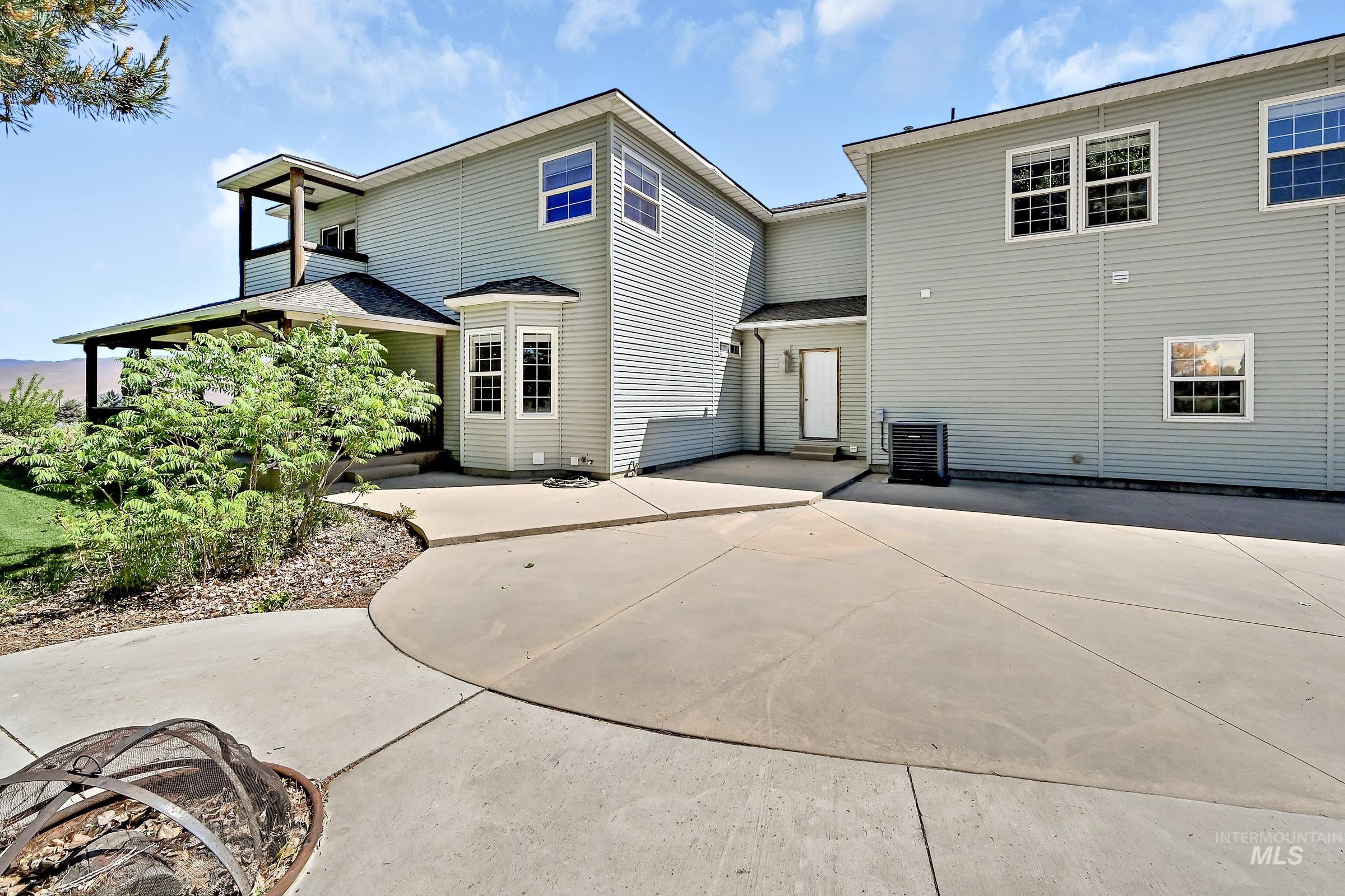 7213 East Columbia Road Boise, ID 83716 - Photo 36 of 47 Rear exterior featuring light gray siding, expansive concrete patio, bay window, upper-level balcony with wood columns, and a covered porch