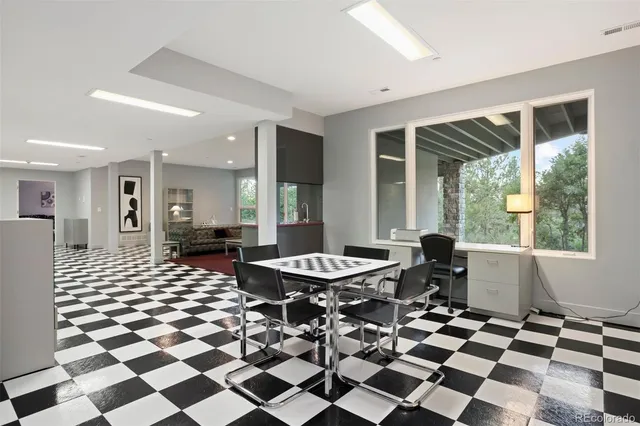a living room with a black white checkered floor with couches chair and a coffee table