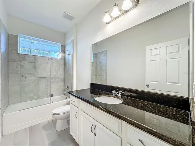 a spacious bathroom with a granite countertop sink a toilet and a mirror