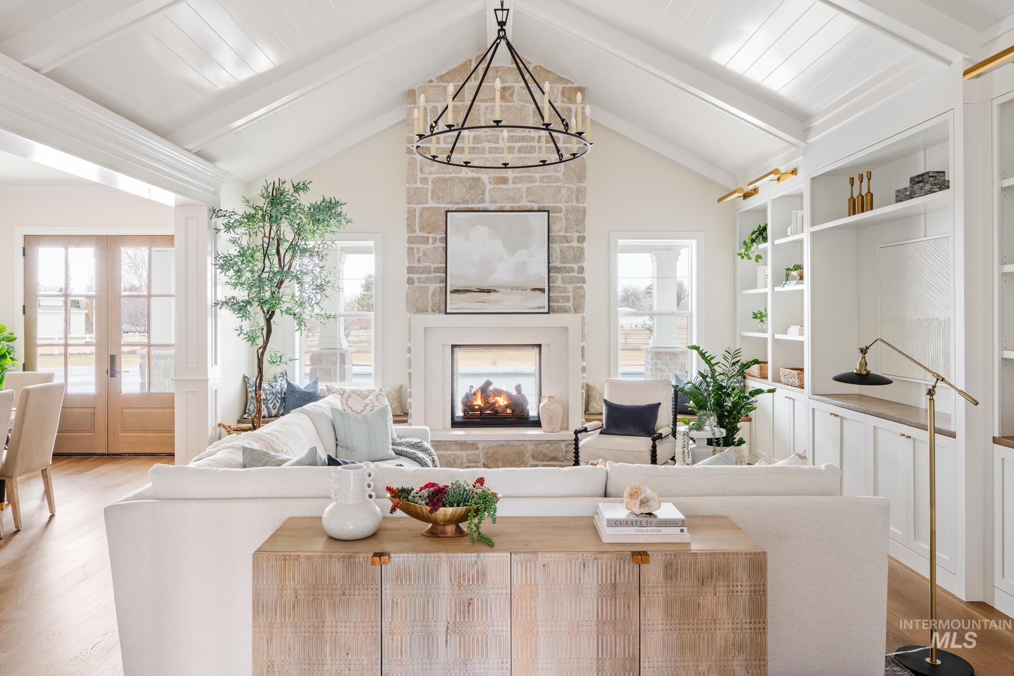 7448 North Cavea Lane Meridian, ID 83646 - Photo 12 of 40 Living area featuring wood finished floors, a fireplace, french doors, and a chandelier