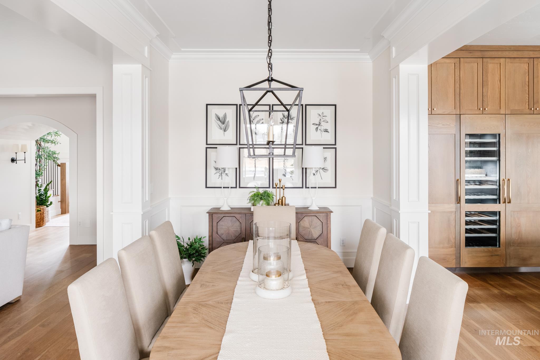 7448 North Cavea Lane Meridian, ID 83646 - Photo 33 of 40 Dining area featuring arched walkways, wood finished floors, ornamental molding, a decorative wall, and a wainscoted wall